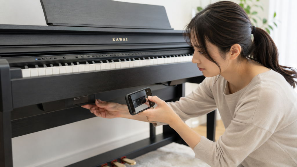 KAWAI電子ピアノの型番や状態を確認して査定用写真を撮る女性